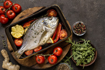 Wall Mural - Dorado fish with fresh vegetables and herbs on a dark background