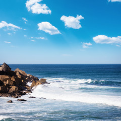 Wall Mural - Beautiful rocky beach and ocean wave under blue cloudy summer sky. California, USA