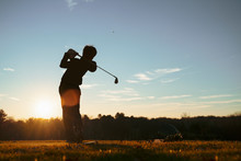 Young Junior Golfer Practicing In A Driving Range With Beautiful Sunset Light In Winter.