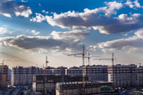 Fototapeta Miasto - construction site in cloudy weather with cranes, construction wagons