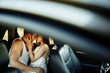 Amazing caucasian couple kissing on the back bench of the car while resting near the road while traveling by car.