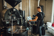 Young Man Coffee Roaster Working In Roastery, Coffee Roasting In Specialty Coffee Roastery.