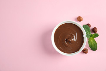 Dessert bowl with sweet chocolate cream, hazelnuts and mint on color background, top view. Space for text