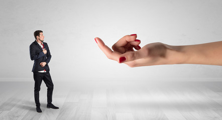 Businessman with kisses on his face in an empty space where a big hand baiting him
