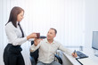 © Bojan Topalovic - Pretty young lady giving a cup of coffee to a male businessman who sit behing the desk ih the office.