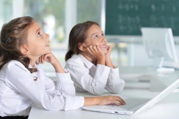 Canvas Print - Portrait of two beautiful little girls at class with laptop