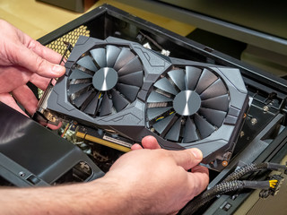 Installing a computer video card in an open system case. Video card in hands