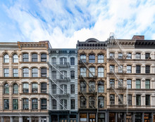 Exterior View Of Old Apartment Buildings In The SoHo Neighborhood Of Manhattan In New York City With Empty Blue Sky