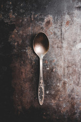 Old metal spoon on the rustic background. Selective focus.