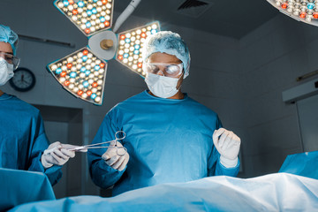 Wall Mural - nurse and surgeon in uniforms and medical masks doing operation