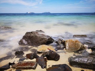 The beautiful silky smooth water waves and rocks on the sea shore.