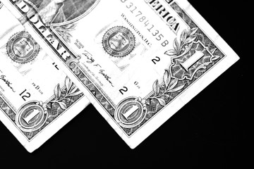 Two one dollar bills on a dark background close up in monochrome