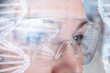 © natali_mis - A female face in virtual reality glasses with dna image model reflection on them.