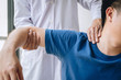 © Ngampol - Doctor physiotherapist assisting a male patient while giving exercising treatment massaging the shoulder of patient in a physio room, rehabilitation physiotherapy concept
