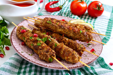 Wall Mural - Tasty lula kebab on the plate on a white wooden table. Chopped meat on wooden skewers, grilled. Eastern cuisine.