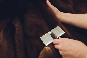 Dry cleaning business concept. Woman working with fur coat and brush.