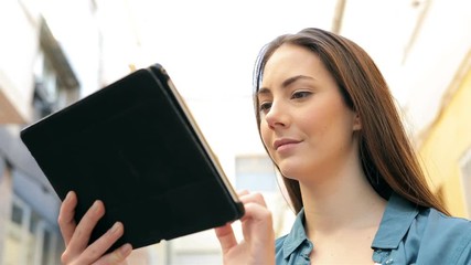 Wall Mural - Serious woman using a tablet browsing online content standing in the street