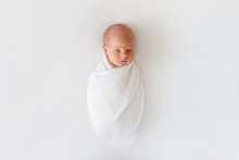 Newborn Baby Sleeps In White Winding On A White Background