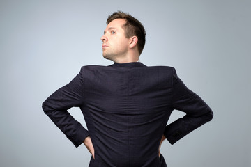 Young man wearing his suit on backwards, gray background.