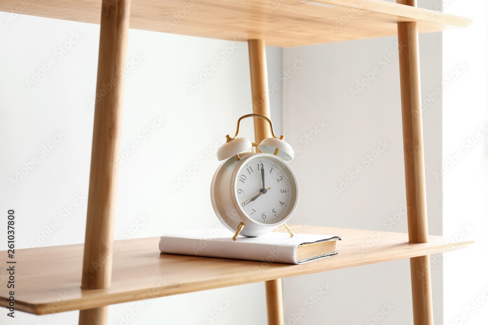 Book and clock on shelf in room