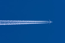 Airplanes Leaving Contrail Trace From Left To Right On A Clear Blue Sky.