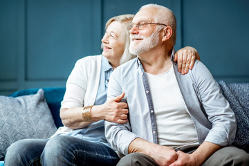 Wall Mural - Portrait of a beautiful senior couple embracing each other, sitting on the couch at home