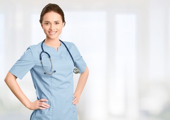 Young female doctor with stethoscope on blurred hospital background