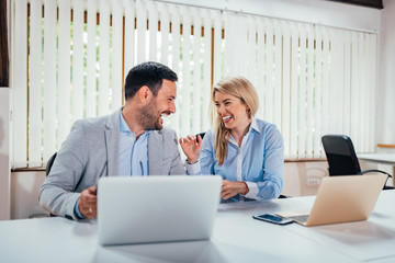 Wall Mural - Two business partners laughing in bright office.