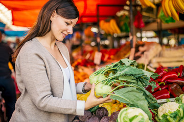 Beautiful woman buying kohlrabi at market.