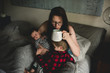 © Courtney Rust/Stocksy - A mother sits in bed with her kids.