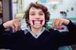 © Angela Lumsden/Stocksy - Boy holding retractors to expose his teeth at the orthodontist office