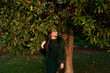 © Lyuba Burakova/Stocksy - Young woman against magnolia leaves in sunset light