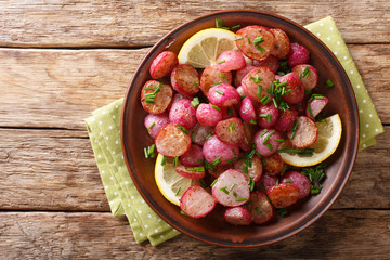 Fried radish with lemon and green onions close-up on a plate. Horizontal top view