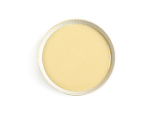 Bowl with condensed milk on white background, top view. Dairy product