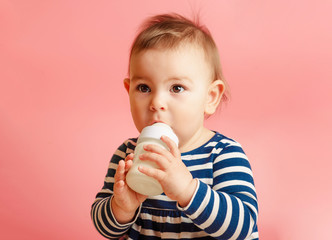 Wall Mural - Portrait of a cute toddler drinking milk from the bottle, one year old food concept