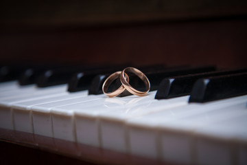 two gold wedding rings on the piano keys