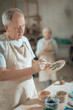 © Yakobchuk Olena - Waist up of elderly craftsman working in potter's studio