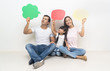 Happy multiethnic family holding blank colorful speech bubbles and looking up at home.