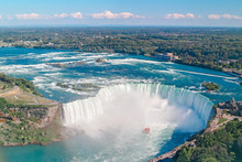 Aerial Top Landscape View Of Niagara Falls  Between United States Of America And Canada. Horseshoe Of Canadian Waterfall On Sunny Day. Water Tour Boat At Famous Tourist Landmark