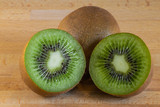 Fototapeta  - Kiwi fruit cut in half in-front of another kiwi fruit