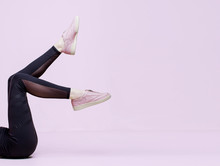 Stylish Female Shoes In Pastel Colors. Flat Lay. Beautiful Woman Legs In Pink Sneakers And Black Leggings On Pink Background. Beauty, Fashion, Trendy Sportswear, Minimal Idea Creative Concept.
