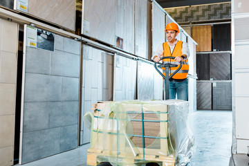 Wall Mural - smiling warehouse worker carrying pallet jack in tiles department