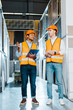 © LIGHTFIELD STUDIOS - handsome multicultural colleagues in safety vests and helmets talking in tiles department