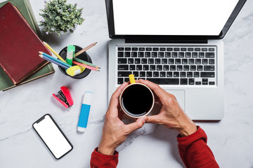 Wall Mural - top view, flat lay.man hands holding cup of coffee on office desk with blank screen laptop and smart