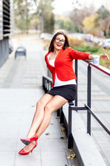 Wall Mural - Young business woman sitting on the fence and relax in pause near the office and smile