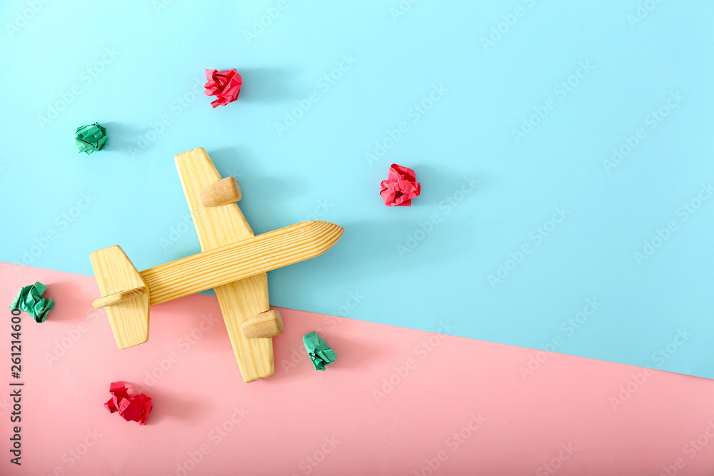 Wooden airplane with crumpled paper on color background. Travel concept