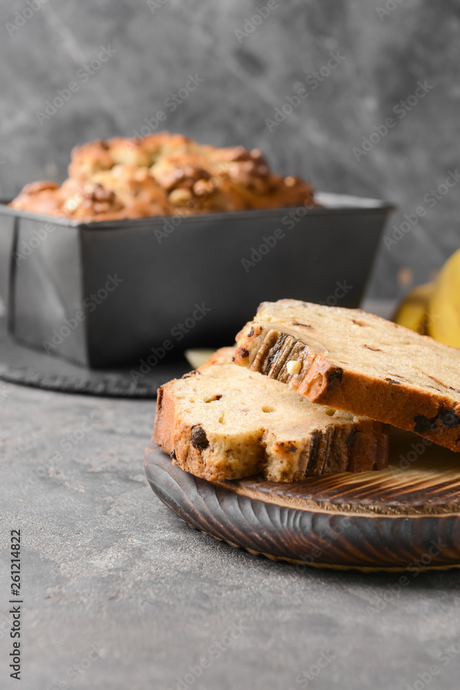 Wooden board with tasty banana bread on grey table
