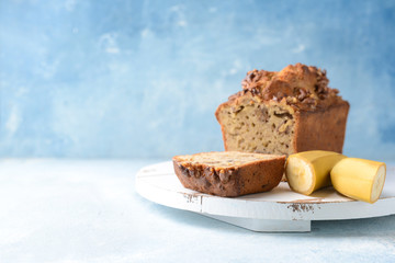 Board with tasty banana bread on color background