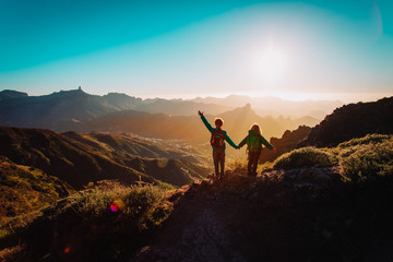 happy boy and girl travel in mountains at sunset, kids enjoy hiking