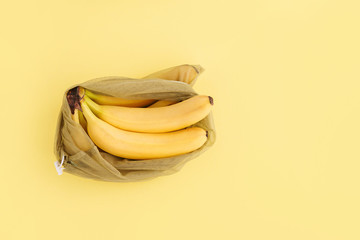 Reusable bag with bananas on yellow background. Zero waste and plastic free shopping concept.